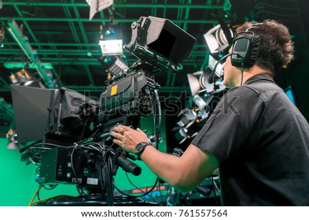 Cameraman taking a broadcast camera in broadcast television virtual green screen studio room.