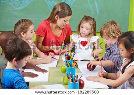 Children learning writing together in preschool with nursery teacher