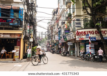 Hanoi, Vietnam - May 18, 2016: Woman wearing the traditional Vietnamese hat cycling in a street of Hanoi's Old Quarter.