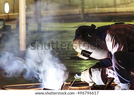 Male worker wearing protective clothing and repair welding industrial construction oil and gas or storage tank inside confined spaces.