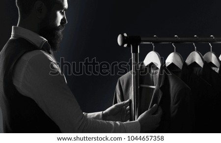 Tailor, tailoring. Men's suit, tailor in his workshop. Elegant man's suits hanging in a row. Luxury mens classic suits on rack in elegant men's boutique. Black and white