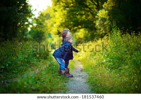 Two brothers having fun in the green wet forest after the rain on a sunny summer day