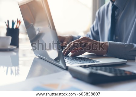 Business man or accountant working on laptop computer with business document, graph diagram and calculator on office table