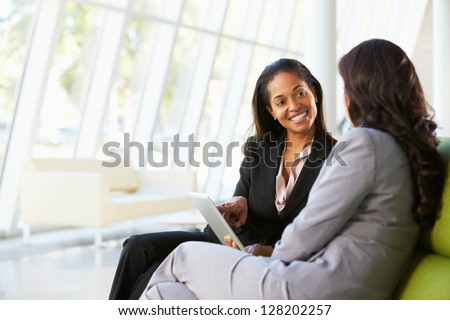 Businesswomen With Digital Tablet Sitting In Modern Office