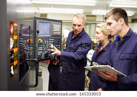 Engineer Teaching Apprentices To Use Computerized Lathe