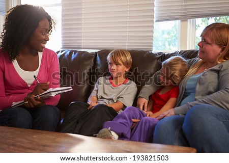 Social Worker Talking To Mother And Children At Home