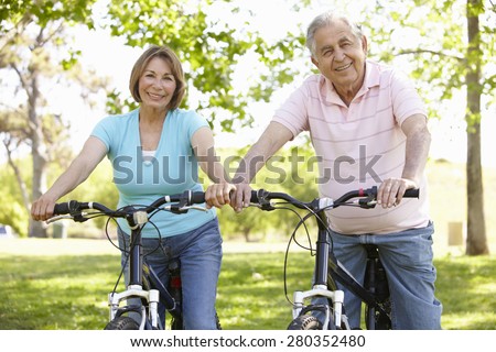 Senior Hispanic Couple Cycling In Park