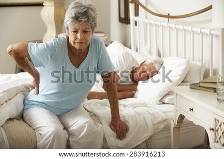 Senior Woman Suffering From Backache Getting Out Of Bed