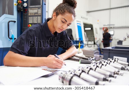 Engineer Planning Project With CNC Machinery In Background