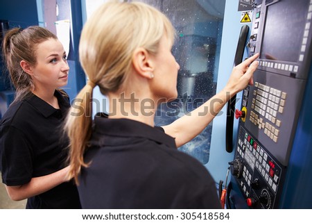 Apprentice Working With Female Engineer On CNC Machinery