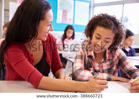 Teacher working with elementary school girl at her desk