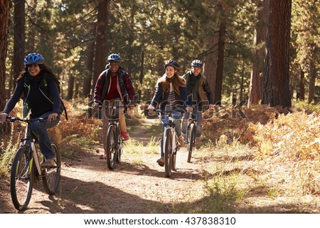Group Four Friends In Helmets Riding Bikes On A Forest Path Group Four Friends In Helmets Riding Bikes On A Forest Path