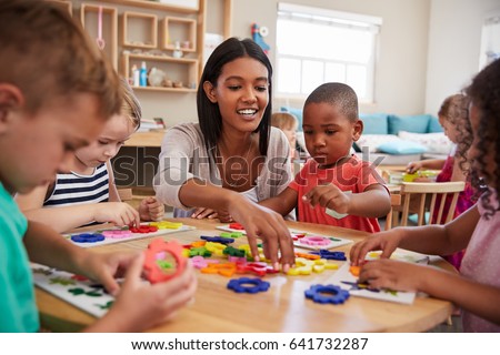 Teacher And Pupils Using Flower Shapes In Montessori School