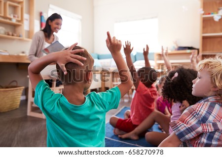 Pupils At Montessori School Raising Hands To Answer Question