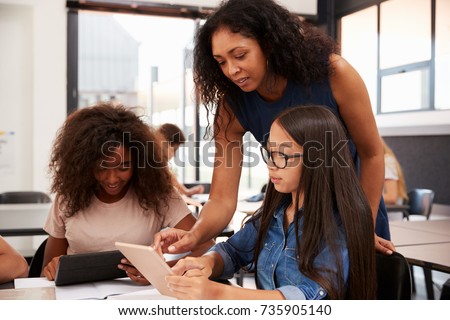 Teacher helping high school students with technology