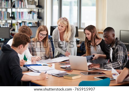 Female Teacher Working With College Students In Library