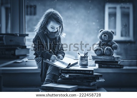 Adorable little girl, writing letter to Santa, sitting on a window, books and teddy bear around