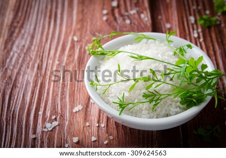 Healthy sea salt with herbs on wooden background