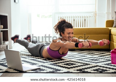 Young woman exercising at home in a living room.
