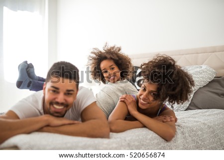 African american family relaxing together in bed.