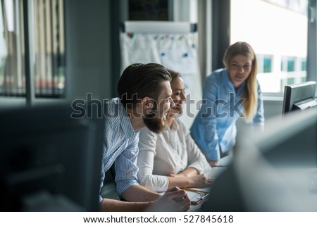 Team of colleagues brainstorming together while working on the computer.