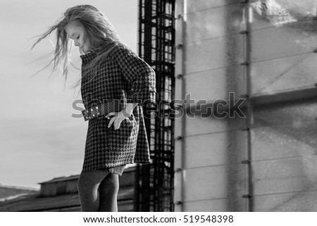 Beautiful young blonde girl in a coat and boots posing for fashion, children's clothing
