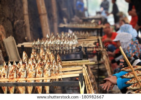 HOA BINH, VIETNAM - MAR 4, 2014: Unidentified local women roasting caught fishes to sell to visitors at an island on Song Da hydro-power lake.