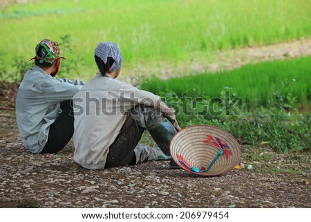 Asian farmers taking a rest on the side of a paddy field after working time. Agriculture is one of the most important industries of the region.