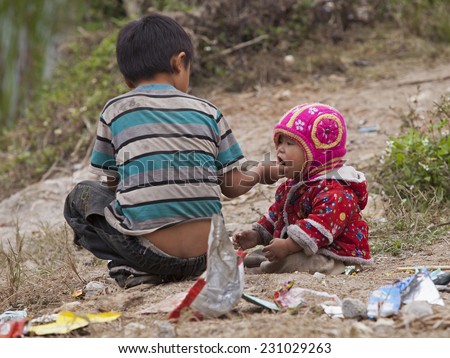 HA GIANG, VIETNAM - NOV 14, 2014: Close up photo of unidentified Hmong child eating candy on the dirty ground in Dong Van rocky plateau. Dong Van rocky plateau is a well known geopark.