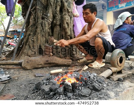 Hung Yen, Vietnam - Aug 11, 2016: Asian blacksmith forging agricultural tools outdoor on a monthly traditional flea market in Nom old village.