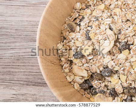 Top view - Muesli flake in wooden bowl on wooden background - Raw food ingredients