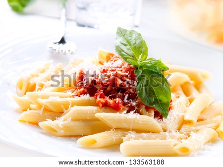 Pasta. Penne Pasta with Bolognese Sauce, Parmesan Cheese and Basil on a Fork. Italian Cuisine. Mediterranean food - stock photo