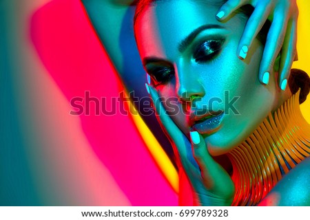 High Fashion model woman in colorful bright lights posing in studio, portrait of beautiful sexy girl with trendy make-up and manicure. Art design, colorful make up. Over colourful vivid background.