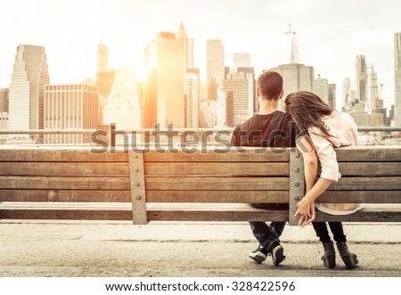 couple relaxing on New york bench in front of the skyline at sunset time. concept about love,relationship, and travel