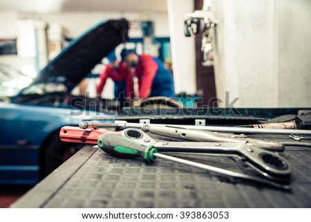 Car mechanics checking the engine - Two men working on in a workshop, close-up on tools