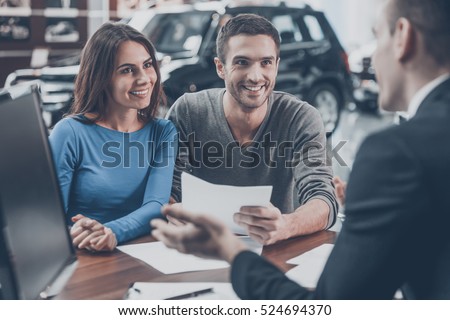 This is good choice. Confident young salesman explaining all the car features to the young attractive owners
