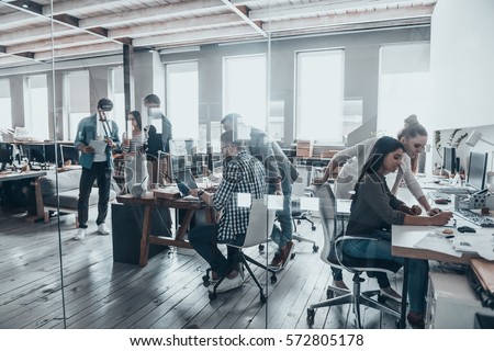 Successful team at work. Group of young business people working and communicating together in creative office