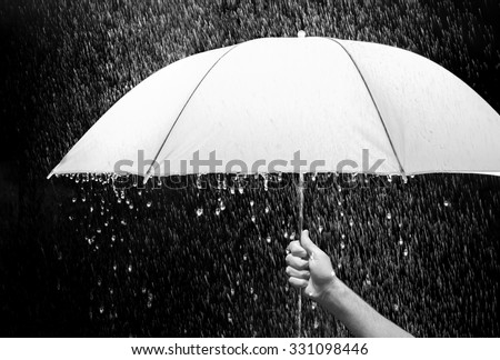 Hand holding an umbrella in rain black background business and fashion concept Hand holding an umbrella in rain black background business and fashion concept