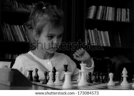 A little girl playing real chess in competition. Black and white photo. Concentrated kid. Power of concentration
