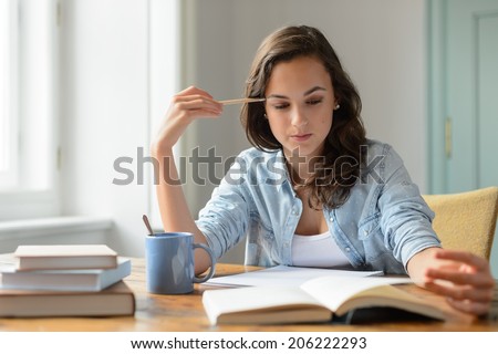 Teenage girl studying reading book at home concentrating looking down