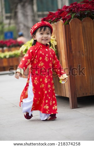 Asia little girl wears Vietnamese traditional long dress ( Ao Dai in Vietnamese) playing on playground by Dinh Tien Hoang street, Hanoi