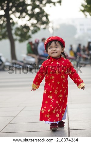 Asia little girl wears Vietnamese traditional long dress ( Ao Dai in Vietnamese) playing on playground by Dinh Tien Hoang street, Hanoi
