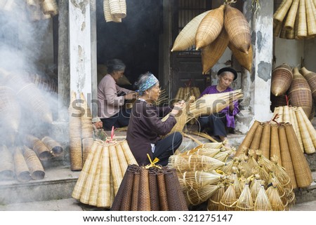 Hung Yen, Vietnam - July 26, 2015: Old women weaves bamboo fish trap at Vietnamese traditional crafts village Thu Sy, Hung Yen province.
