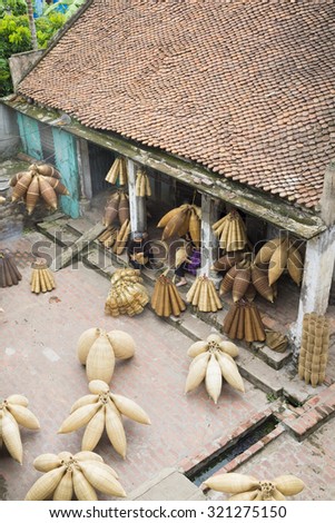 Hung Yen, Vietnam - July 26, 2015: Old women weaves bamboo fish trap at Vietnamese traditional crafts village Thu Sy, Hung Yen province.