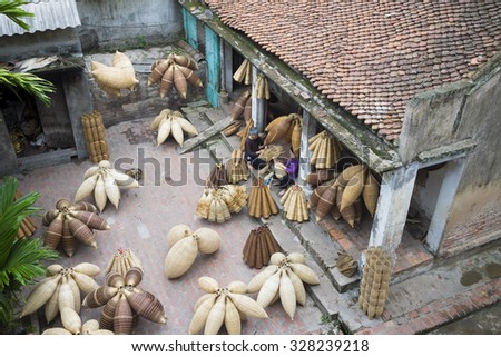 Hung Yen, Vietnam - July 26, 2015: Old women weaves bamboo fish trap at Vietnamese traditional crafts village Thu Sy, Hung Yen province.