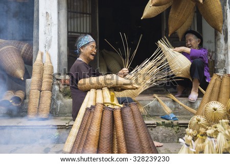 Hung Yen, Vietnam - July 26, 2015: Old women weaves bamboo fish trap at Vietnamese traditional crafts village Thu Sy, Hung Yen province.