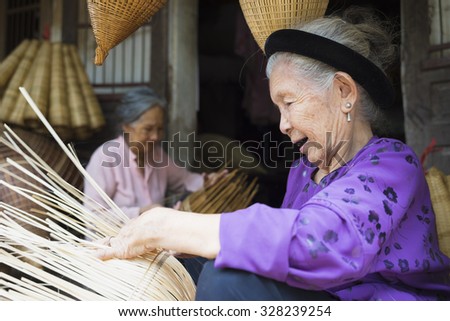 Hung Yen, Vietnam - July 26, 2015: Old woman weaves bamboo fish trap at Vietnamese traditional crafts village Thu Sy, Hung Yen province.