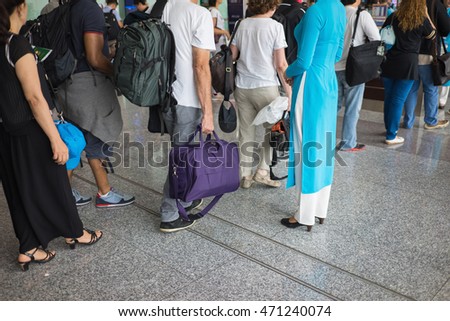Queue of people in Noi Bai airport, Vietnam. Focus on female staff wearing Vietnamese long dress Ao Dai