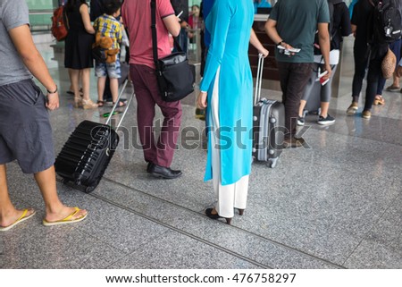 Close-up Queue of people in Noi Bai airport, Vietnam. Focus on female staff wearing Vietnamese traditional long dress Ao Dai