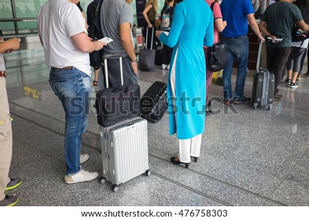 Close-up Queue of people in Noi Bai airport, Vietnam. Focus on female staff wearing Vietnamese traditional long dress Ao Dai